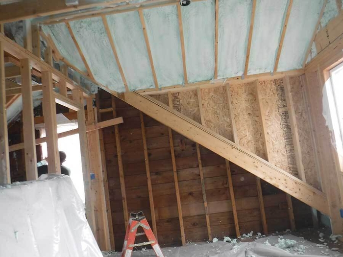 Contractors installing wall and ceiling insulation in a home renovation