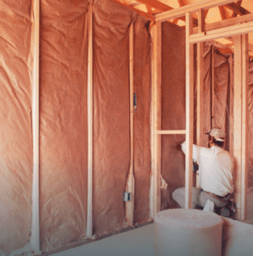 Contractor installing batt insulation in wall framing