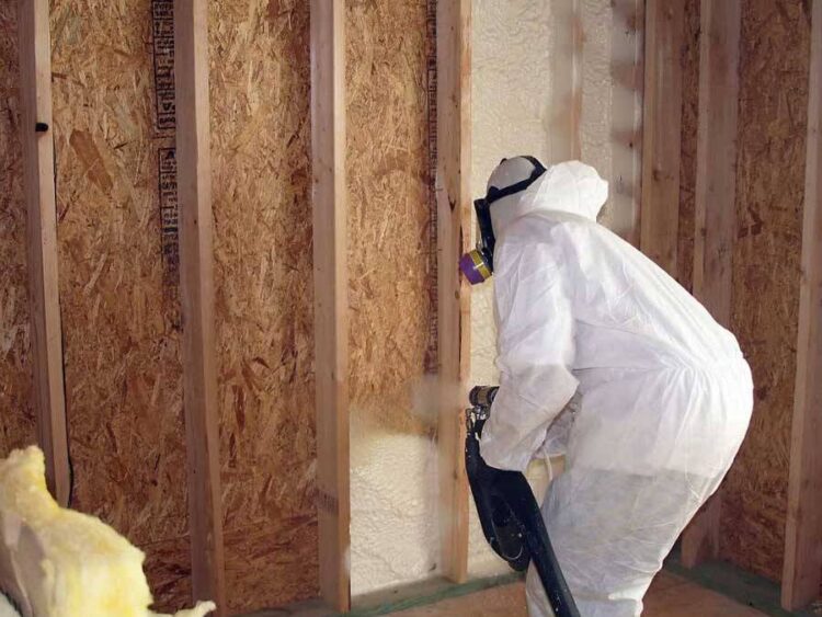 Technician applying spray foam insulation on wall for energy efficiency