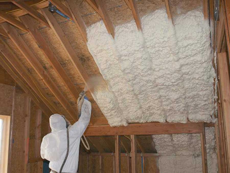 Worker applying spray foam insulation on the attic ceiling for energy efficiency