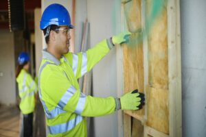 Workers installing fiberglass batt insulation in a wall cavity