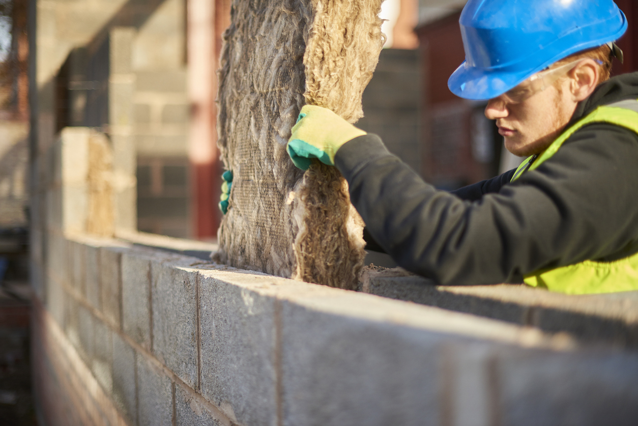 Construction worker placing insulation material in cavity wall structure